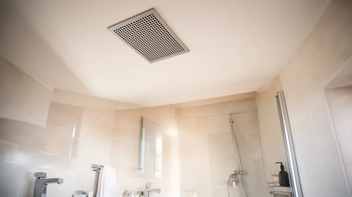 Bouche de ventilation extra plate discrète dans une salle de bain moderne avec plafond bas